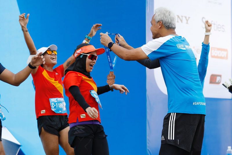 Gubernur Jawa Tengah Ganjar Pranowo mengalui medali kepada istrinya, Siti Atikoh yang debut di ajang maraton Pocari Sweat Run Indonesia 2022 di Kota Bandung. Foto: Humas Jateng.
